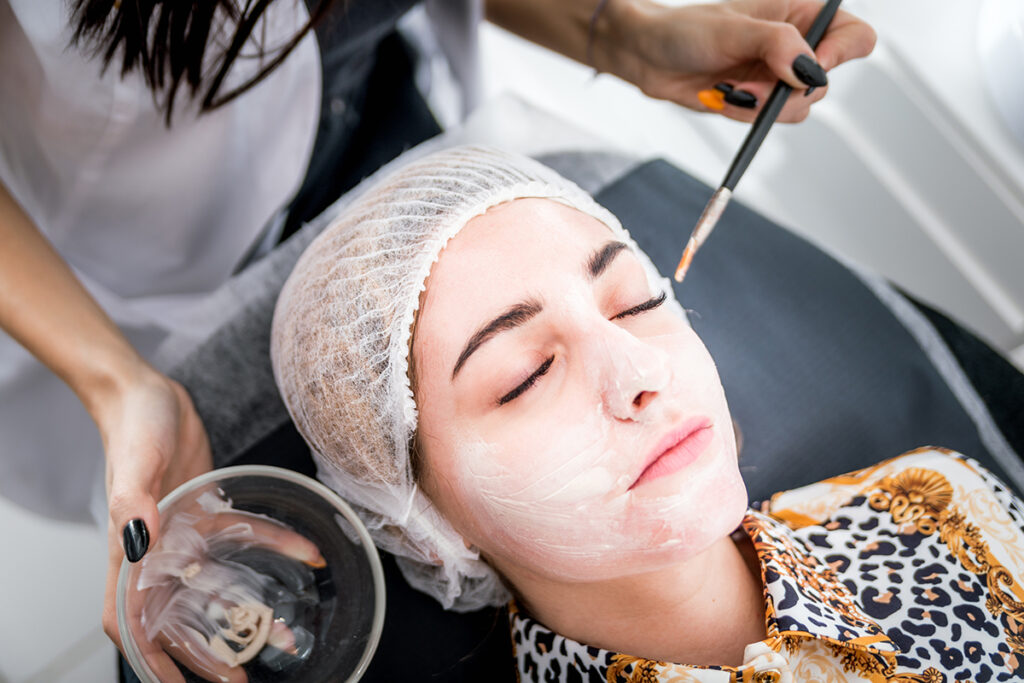 Beautician applying facial mask at beauty salon, cosmetology treatment skincare face zupa